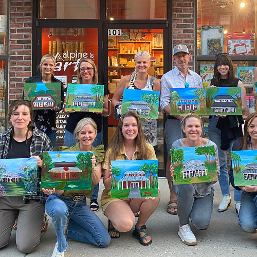 Roundup River Ranch fundraising paint event. Group of attendees holding their Trent's Cabin painting.