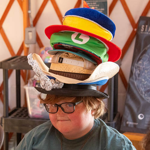Camper being funny with a stack of hats on his head.