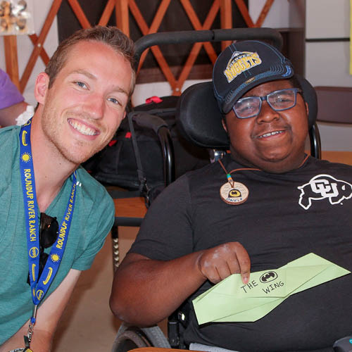 Camper and volunteer smiling at camera.