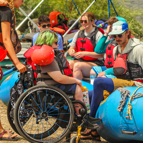 Roundup River Ranch alumni in wheelchair loading in to a raft with help of counselor
