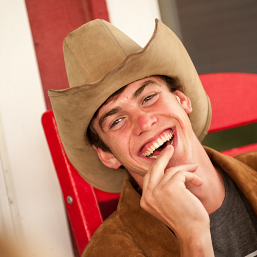 smiling camp volunteer wearing a cowboy hat
