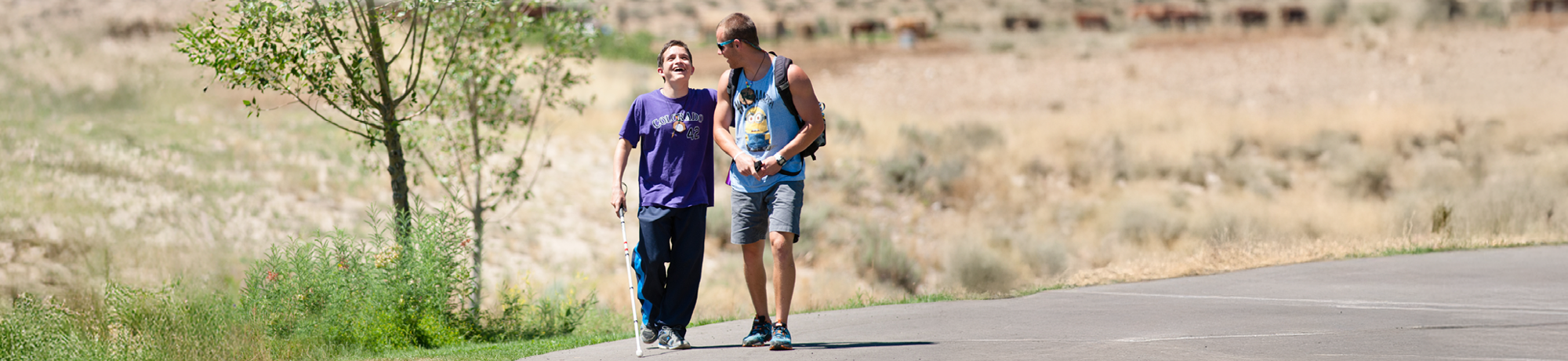 blind camper and camp counselor walking and laughing.