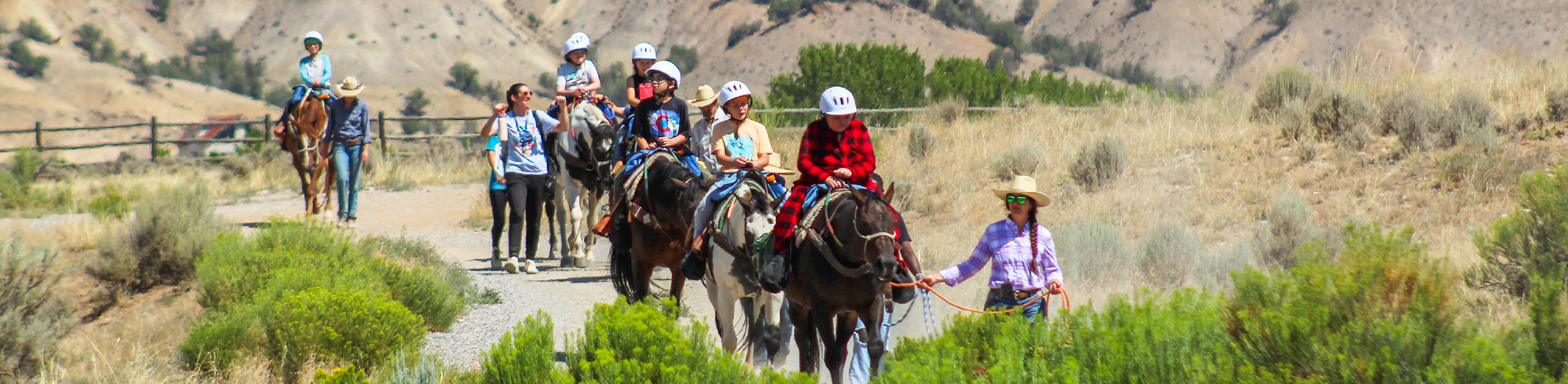 Volunteers leading horses and campers through landscape