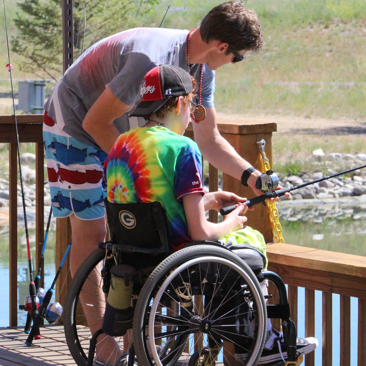 camper in wheelchair fishing with counselor