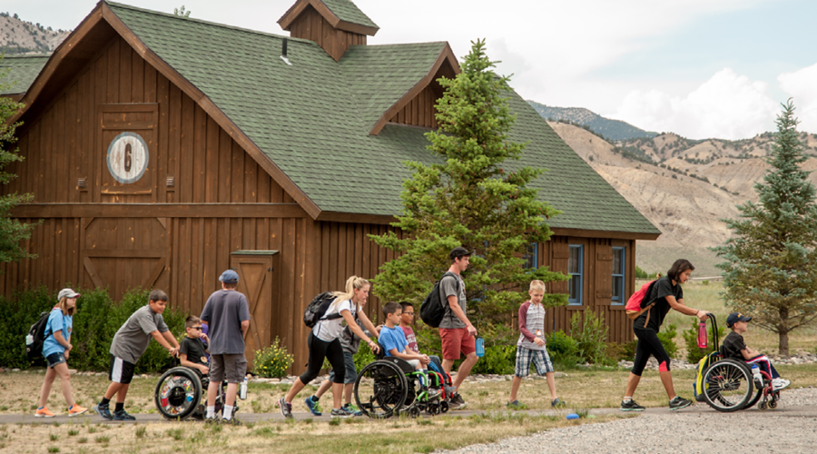 Volunteers pushing campers who are in wheelchairs at Roundup River Ranch